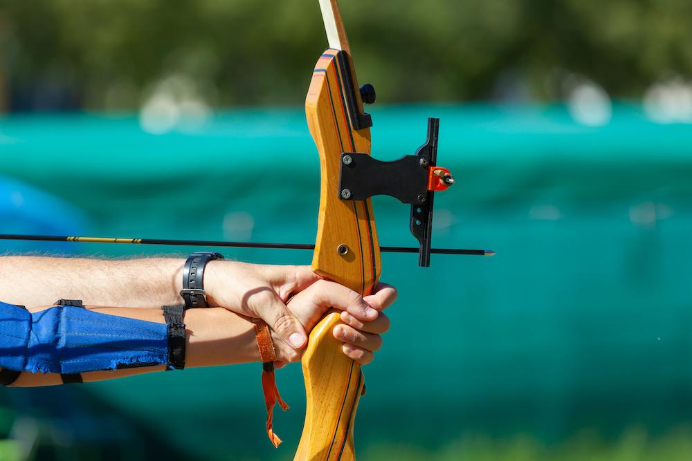 Person holding a bow and arrow outdoors.