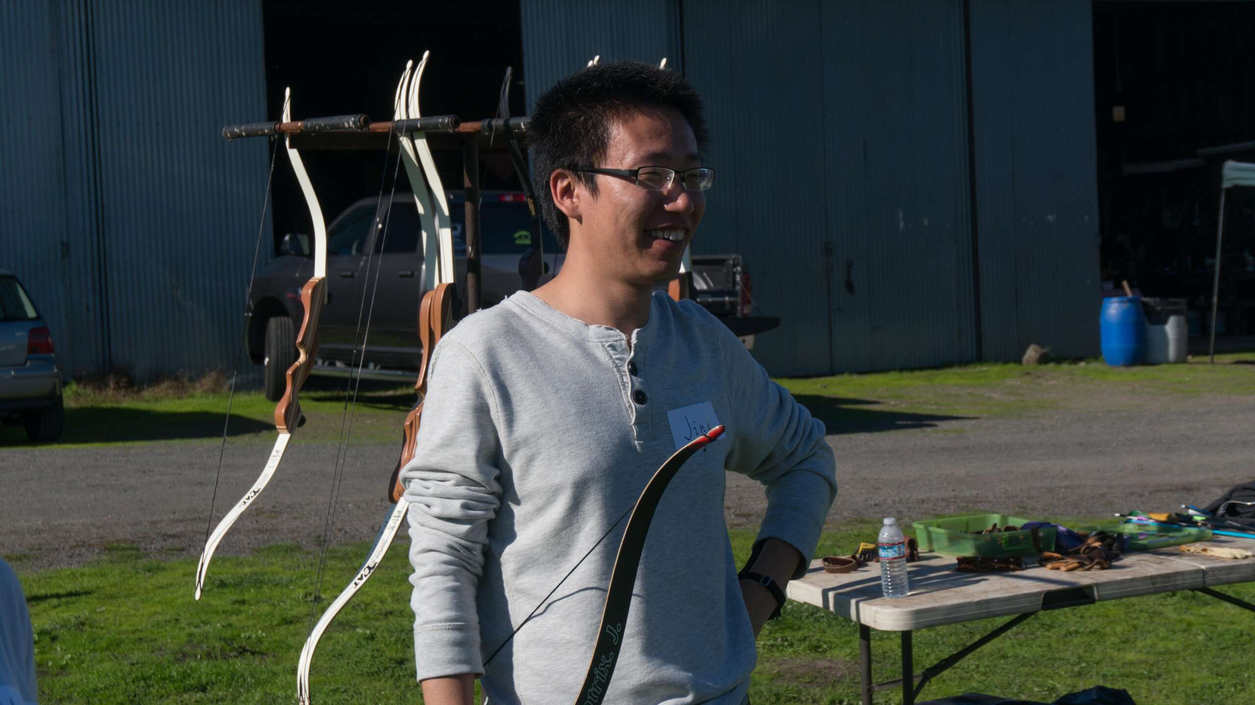 A man wearing glasses holding a bow outdoors.